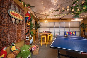 A room with a ping pong table, a dartboard, and a sign that reads 'ENCHANTED TIKI ROOM'. - Beautiful Pool Home with Games Room Near Attractions (Kissimmee)