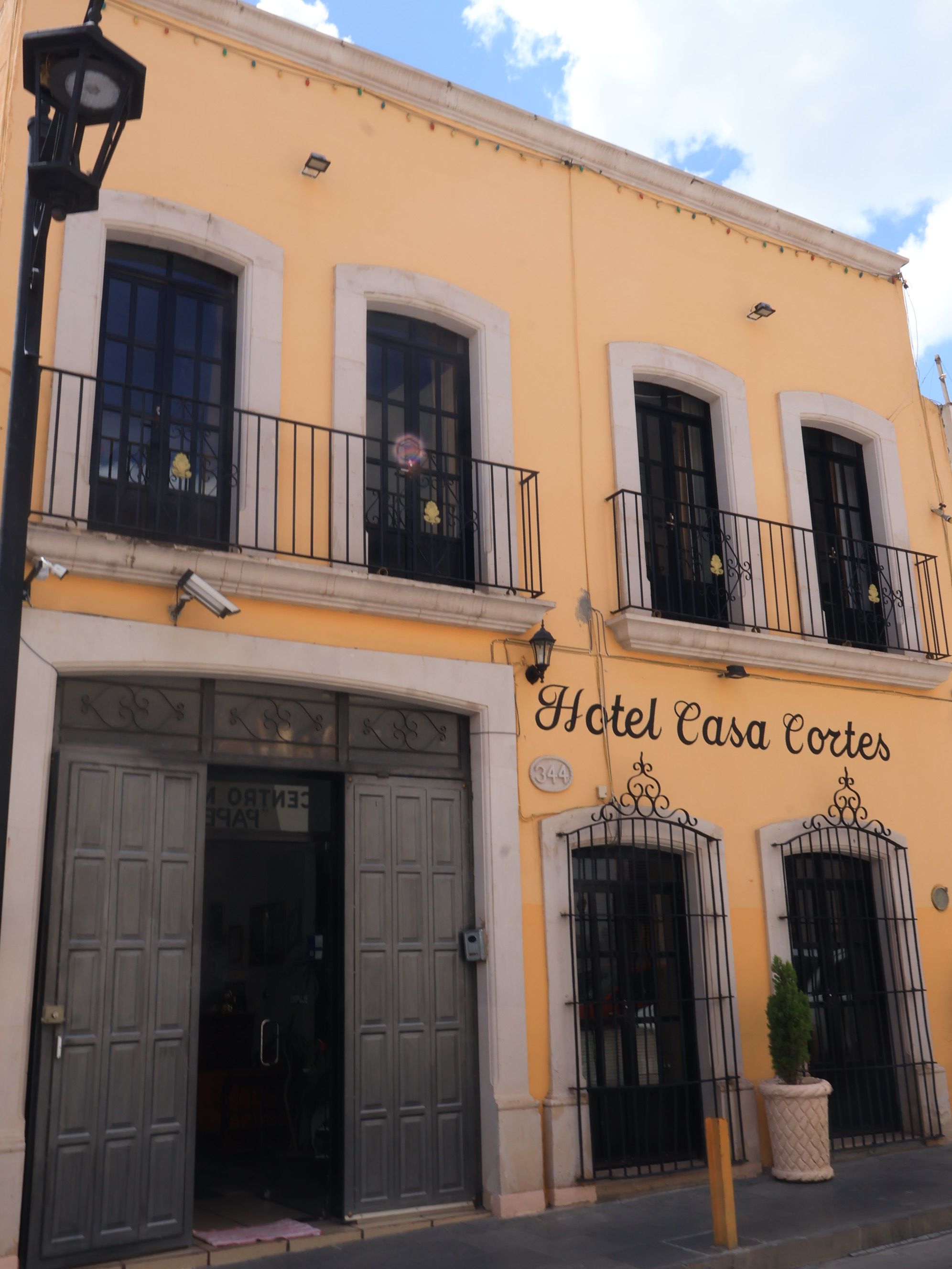Un edificio con un letrero que dice 'Hotel Casa Cortes' y una entrada amplia con puertas dobles.