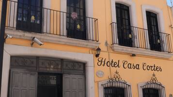 Un edificio con un letrero que dice 'Hotel Casa Cortes' y una entrada amplia con puertas dobles.