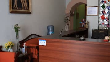 Un área de recepción con un mostrador de madera, un cuadro en la pared y una exhibición de banderas.