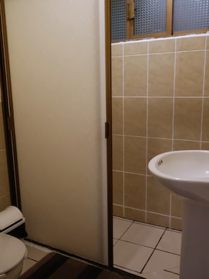 A bathroom with a toilet, a sink, and a shower area. - Hotel Casa Cortes (Zacatecas)