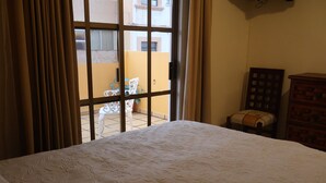 Ein Hotelzimmer mit einem Bett, einem Vorhangfenster, einem Sessel und einem Holzschrank.