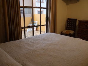 A hotel room with a bed, a window with curtains, a chair, and a wooden cabinet. - Hotel Casa Cortes (Zacatecas)