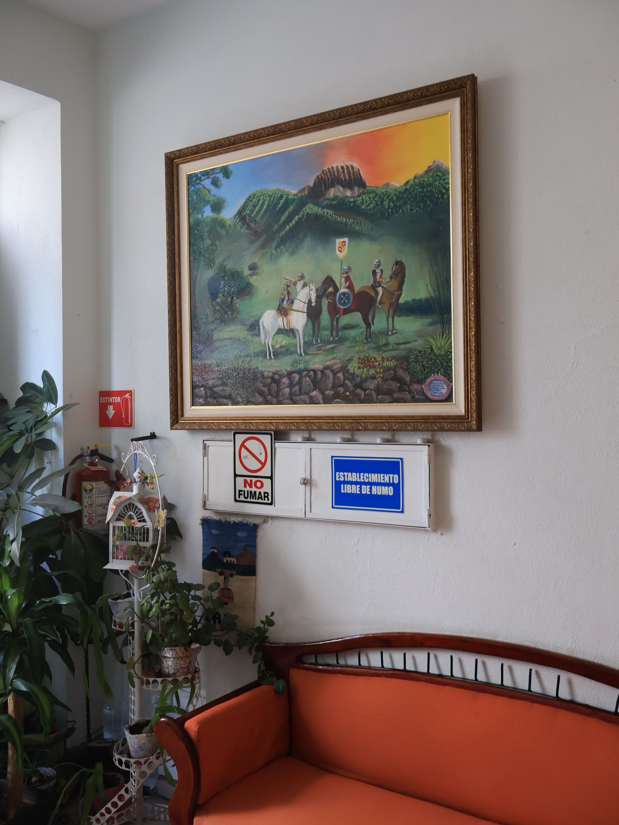 A room with a framed painting, a fire extinguisher, a no-smoking sign, a no-fumage sign, and a humidity-free establishment sign.