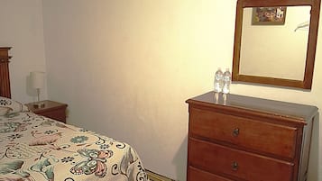 Un dormitorio con cama, tocador, espejo, mesita de noche y lámpara.