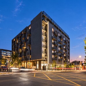 A multi-story building with balconies, a ground-level entrance, and a parking area. - El mejor lugar - Estacionamiento - Wi-Fi (Santiago)