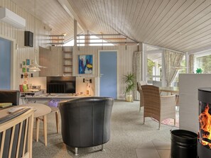 Ein geräumiger Wohnbereich mit Kamin, Esstisch und Küchenzeile inklusive Fernseher.