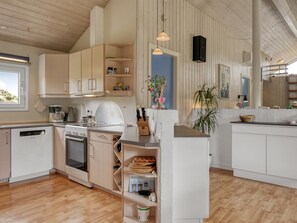 Eine moderne Küche mit Holzausstattung, einem Einbauofen und einem Essbereich mit Tisch und Stühlen.