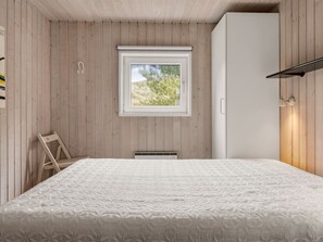 Un dormitorio con cama, ventana, armario y una silla.