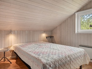 Un dormitorio con cama, escritorio y ventana.