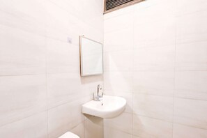 A bathroom with a white sink, a mirror, and tiled walls. - Hotel O Rangpuri Mahipalpur (New Delhi)