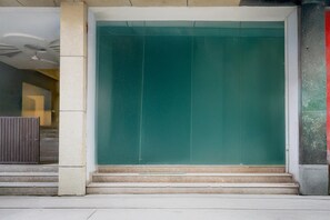 A building entrance with a green door, steps leading up to it, and a concrete pillar to the left. - Hotel O Rangpuri Mahipalpur (New Delhi)