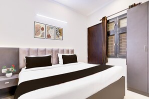 A modern bedroom with a bed, bedside table, artwork, and a wardrobe. - Hotel O Rangpuri Mahipalpur (New Delhi)
