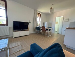 A modern living room with a flat-screen TV, a dining area with chairs, and a kitchen area with a refrigerator. - A Mountain Getaway: Cabin for 2–4 People with Spa Access (AUBURE)