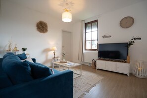A living room with a sofa, coffee table, TV, and decorative items. - A Mountain Getaway: Cabin for 2–4 People with Spa Access (AUBURE)