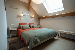 A bedroom with a sloped ceiling, a skylight, a bed with multiple pillows, bedside tables, and a bench. - A Mountain Getaway: Cabin for 2–4 People with Spa Access (AUBURE)