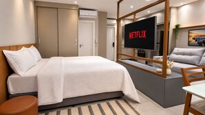 A modern bedroom with a bed, a TV, and a sofa. - Google Translate (Salvador)