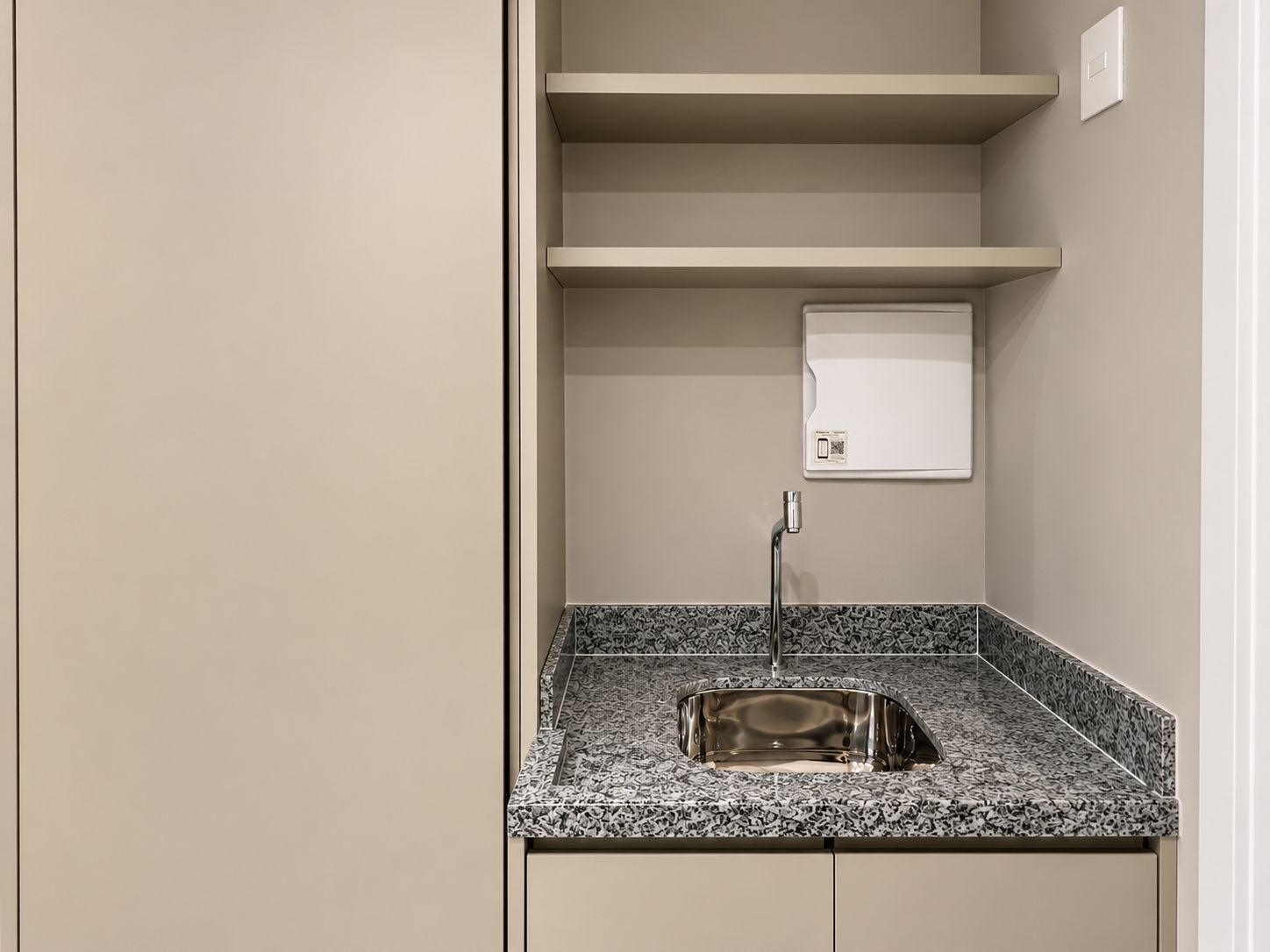 A small bathroom with a granite countertop sink, a mirror, and a wall-mounted light switch.