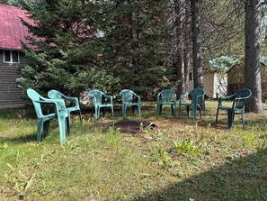 Outdoor seating with chairs arranged in a row, surrounded by grass and trees, with a building in the background. - Boat Launch Access | FirePit | 30MI to YNP (Island Park)