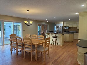 A spacious kitchen with wooden cabinetry, a central island, and a dining area with a table and chairs. - New Milford Oasis - 4 bedrooms 5 1/2 baths (New Milford)