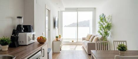 A modern kitchen with a blender, microwave, and dishwasher, leading to a balcony with a view.