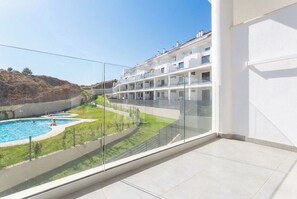 A modern building with a pool and a view of a hilly landscape. - Sunset Med Hills 2BR Fuengirola (Fuengirola)