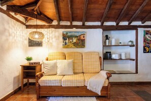 A cozy living room with a wooden ceiling, a checkered sofa, a small table with a plant, and a painting on the wall. - Las Ninfas Natural Escape 4 (Icod de los Vinos)