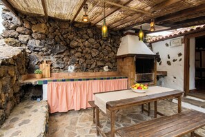 A rustic kitchen with a stone wall, a wooden counter, and a pizza oven. - Las Ninfas Natural Escape 3 (Icod de los Vinos)