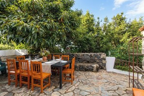 An outdoor patio with stone flooring, wooden furniture, and a table set for dining. - Las Ninfas Natural Escape 3 (Icod de los Vinos)