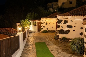 A stone pathway leading to a rustic building with a tiled roof, surrounded by greenery and a wooden fence. - Las Ninfas Natural Escape 3 (Icod de los Vinos)