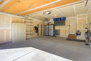 A garage with concrete floor, metal lockers, a bicycle, and a power tool on the right. - Downtown WP Chalet 380 I Private Hot Tub I Great Views I Bunk Room I Discounted Attractions (Fraser)