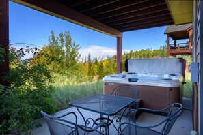 Eine Außenpatio mit Whirlpool, Tisch und Stühlen.