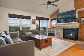 Una sala de estar con chimenea, un sofá, una mesa de centro y vistas al exterior.