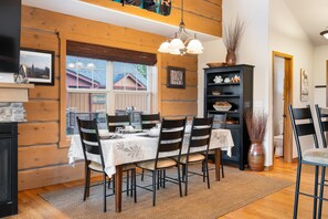 A dining area with a wooden interior, a large window, and a chandelier. - Downtown WP Chalet 380 I Private Hot Tub I Great Views I Bunk Room I Discounted Attractions (Fraser)