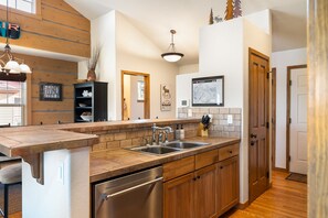 Una cocina moderna con encimera de madera, pileta de acero inoxidable y lavavajillas.