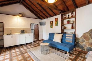 A cozy interior with a kitchen, a blue sofa, and a stone wall. - Las Ninfas Natural Escape 1 (Icod de los Vinos)