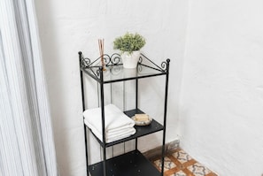 A black metal shelf with a white towel and a bar of soap. - Las Ninfas Natural Escape 1 (Icod de los Vinos)