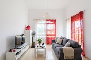 A modern living room with a sofa, TV, and a fan. - Corralejo 3BR House with Pool (Corralejo)