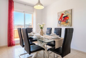 A dining area with a glass table, black chairs, white plates, and a vase of flowers. - Corralejo 3BR House with Pool (Corralejo)