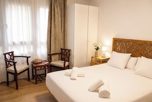 Ein Hotelzimmer mit einem Bett, zwei Sesseln, einem Nachttisch mit Lampe und einem Kleiderschrank.