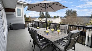 A balcony with a table, chairs, and an umbrella. - Seaview Suite · sunrise deck, BBQ, firepit & 3-bed (Campbell River)