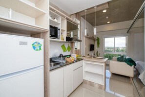 A modern kitchen with white cabinets, a built-in microwave, and a window overlooking a cityscape. - Cozy apt relaxing view - Great Guest Service 604 (Fernando de la Mora)