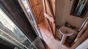 Un baño pequeño con inodoro, lavamanos y un ventanal.