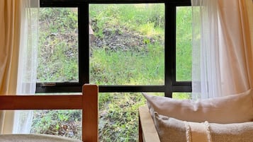 Une pièce chaleureuse avec une grande fenêtre, des meubles en bois et une vue sur la verdure environnante.
