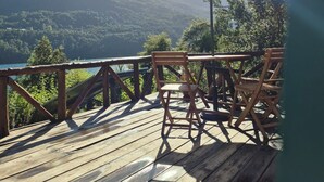 Una terraza de madera con una mesa y sillas, con vista a un paisaje montañoso.