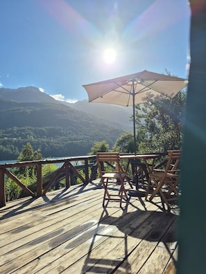 Una terraza de madera con una mesa y sillas, con vista a un paisaje montañoso.