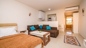 Ein Hotelzimmer mit Bett, einer Couch, einem kleinen Tisch und einer Küchenzeile.