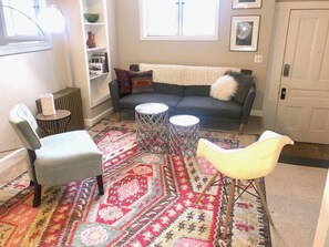 A living room with a sofa, two chairs, a patterned rug, and a bookshelf. - FULLY FURNISHED 1BR 1BA APT IN HISTORIC DOWNTOWN DISTRICT OF ASHEVILLE (Asheville)