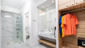 A modern bathroom with a shower area, a sink, and a wooden vanity with hanging clothes. - Premium Suite with veranda and panoramic sea view, Notus Hotel Chania (Chania)