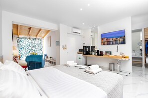Ein modernes Hotelzimmer mit einem großen Bett, einem Schreibtisch mit Computer, einem Fernseher und Blick auf die Stadt.